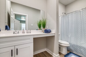 A bathroom with a white vanity, a mirror, a toilet, and a shower curtain. - Cozy home in gated neighborhood! (Houston)