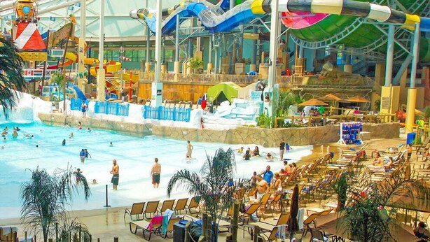 An indoor water park with multiple water slides, a swimming pool, and lounge areas with chairs and umbrellas. - Private Pocono Getaway (Tobyhanna)