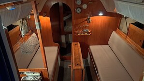 Una cabaña pequeña y bien iluminada con muebles de madera, una mesita y una estufa.