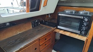 Una kitchenette compacta con estufa integrada, horno tostador y un lavamanos pequeño.