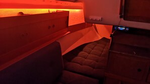 Cama litera con cabecera iluminada en rojo, panel de control y pequeño estante con objetos.