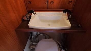 Une petite salle de bain avec un lavabo blanc, des meubles en bois et des toilettes.