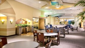 A hotel lobby with round tables and chairs, a reception desk, and a large plant. - 1BD Suite/Daytona - Ocean Walk Guest Suite!! (Daytona Beach)