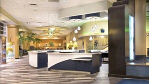 A hotel lobby with a reception desk, seating area, and decorative plants. - 1BD Suite/Daytona - Ocean Walk Guest Suite!! (Daytona Beach)