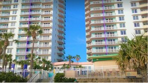 A multi-story hotel with balconies, palm trees, and a clear blue sky. - 1BD Suite/Daytona - Ocean Walk Guest Suite!! (Daytona Beach)