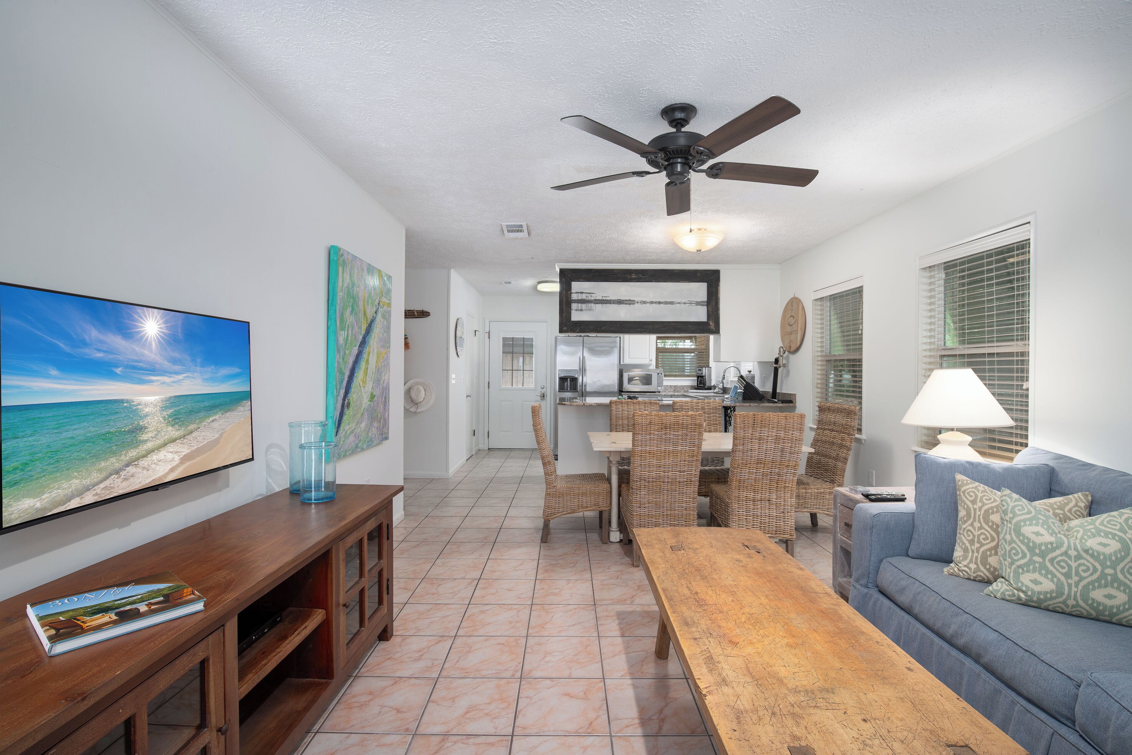 A living room with a TV, wooden entertainment unit, and a blue sofa.
