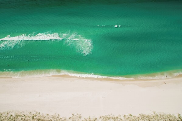 Une plage à l’eau turquoise et limpide et au sable blanc.