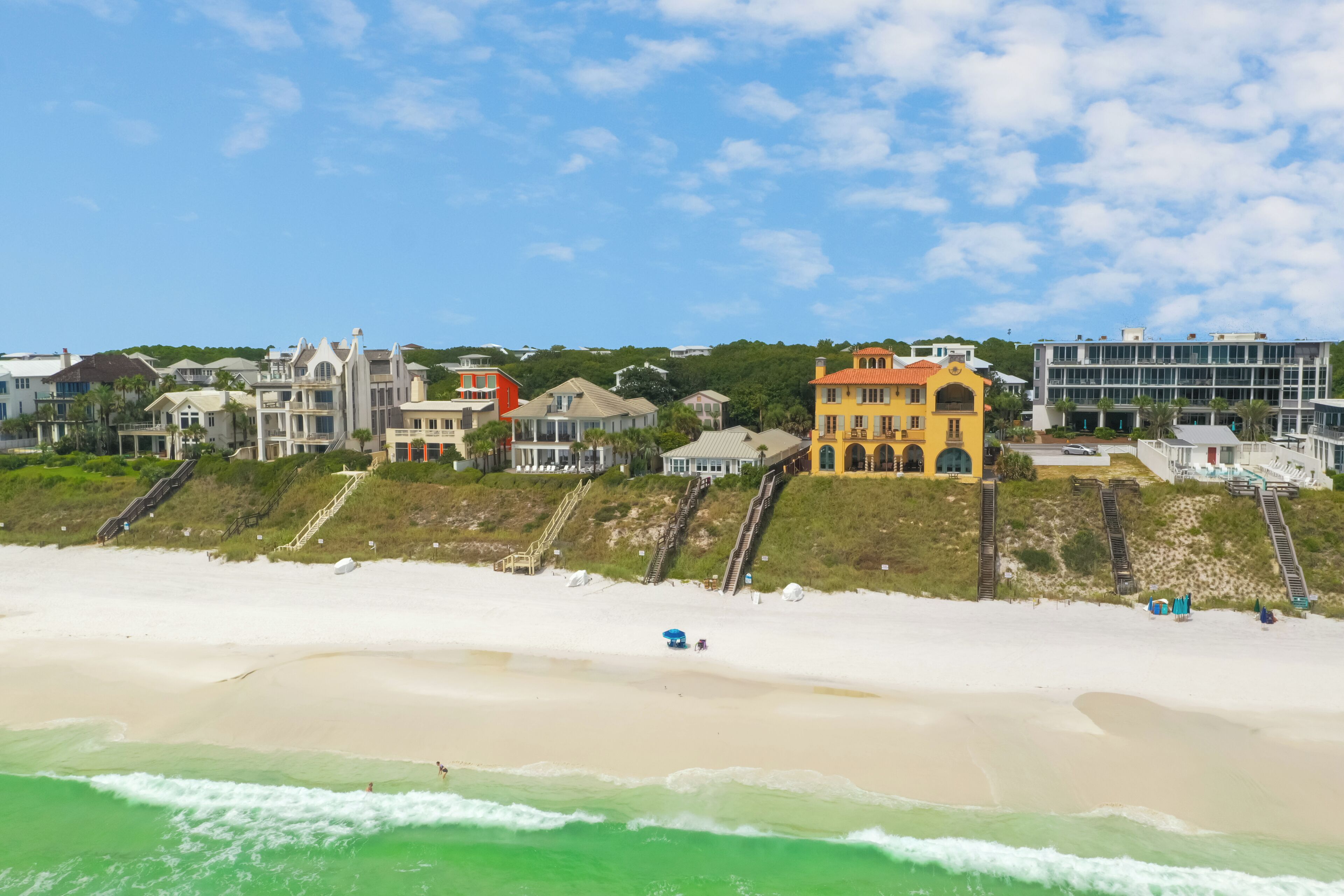 A coastal area with beachfront properties, including a yellow building with a red roof and a white building with a balcony.