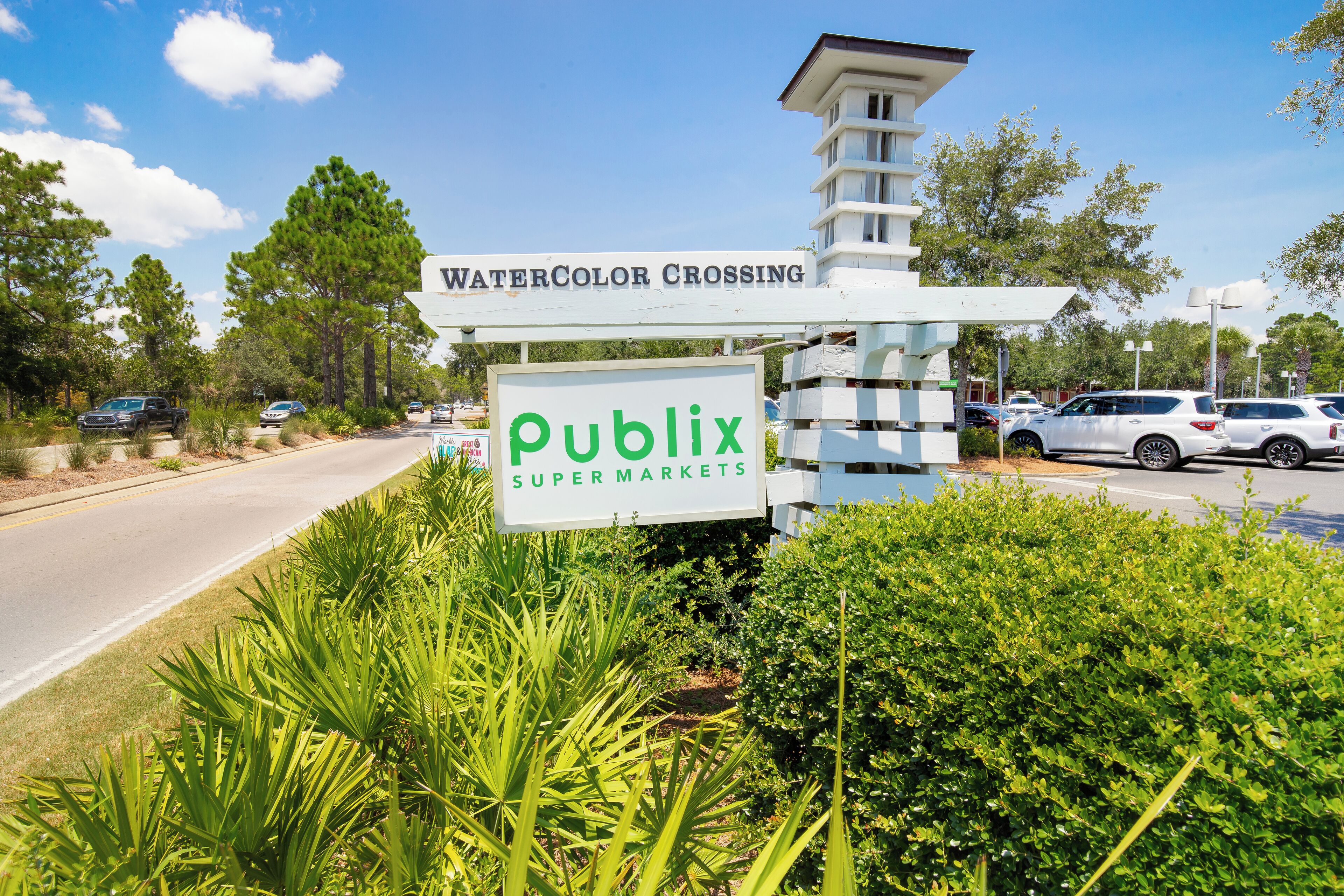 Une enseigne d’un supermarché Publix à un carrefour, avec une route et des voitures garées.