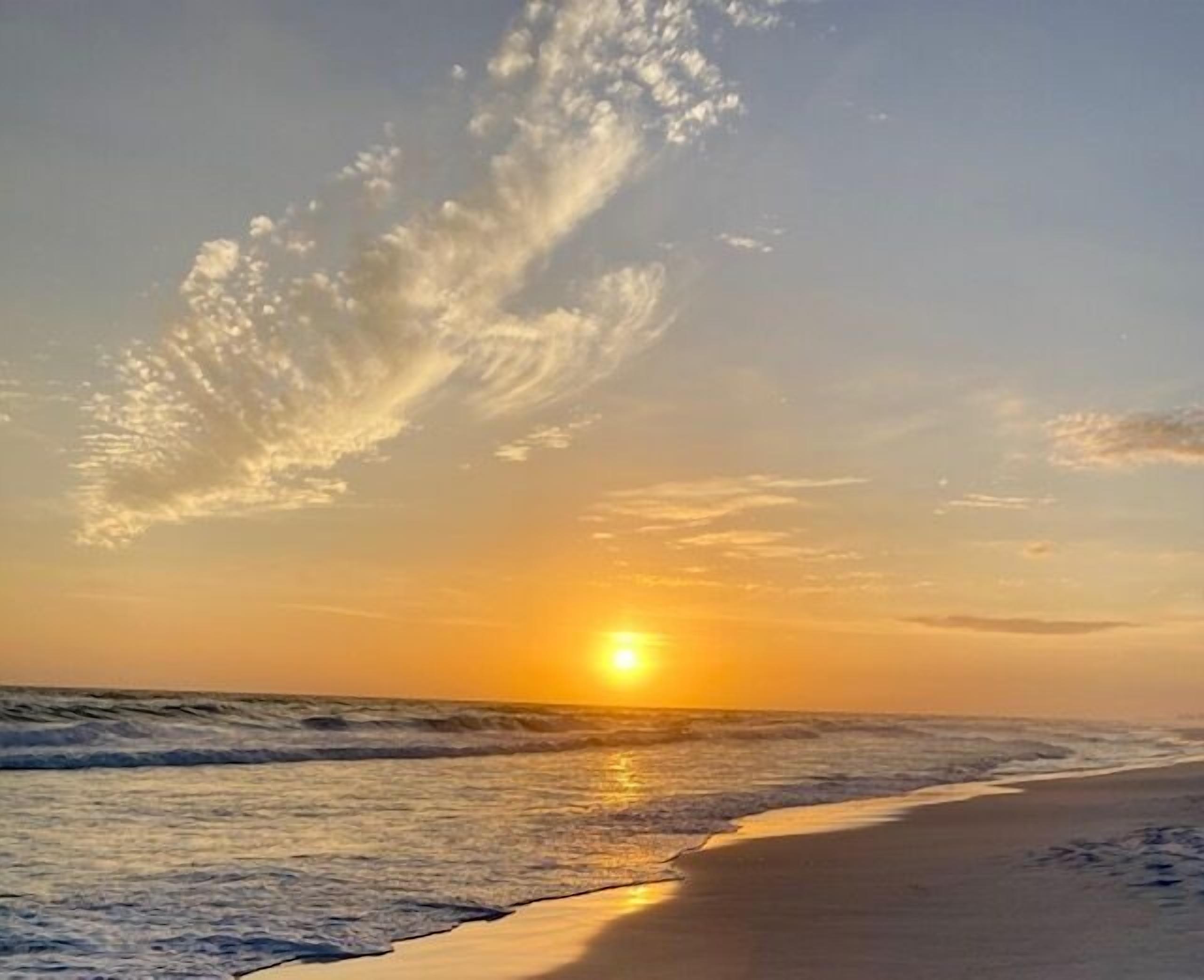 Une plage avec des vagues au coucher du soleil.