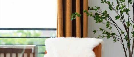 Una sala moderna con una silla de madera, un sofá, una mesita y una planta en maceta.
