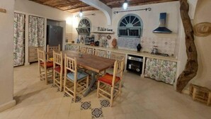Une cuisine rustique avec des poutres en bois, un coin repas avec une table et des chaises en bois, et un four encastré.