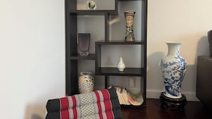 A bookshelf with various decorative items, including vases and a patterned cushion.