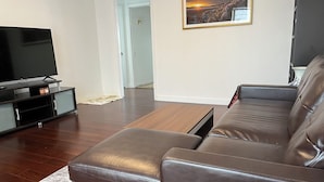 A modern living room with a leather sofa, a flat-screen TV on a stand, and a framed picture on the wall.