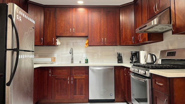 A modern kitchen with wooden cabinets, stainless steel appliances, and a skylight.