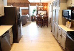 A kitchen with wooden cabinets, a dining area with a chandelier, and a microwave on the countertop. - Lakefront with
Stunning Views! (Creal Springs)
