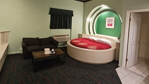 A room with a round bed, a sofa, a small table, and a radiator.
