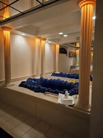 A hotel bathroom with large columns, a mirror, and blue bath mats.