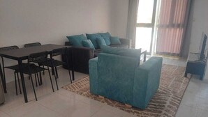 A living room with a sofa, a dining table with chairs, and a TV. - La bonita compound  (Hurghada)