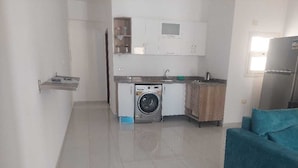 A compact living space with a washing machine, a kitchenette, and a teal sofa. - La bonita compound  (Hurghada)