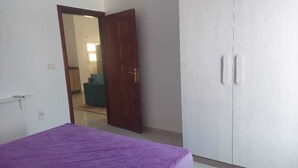 A bedroom with a bed, a wardrobe, and a door leading to another room. - La bonita compound  (Hurghada)