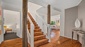 Um interior espaçoso com escada de madeira, um espaço de estar acolhedor e vista para o exterior.