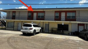 A multi-story building with numbered doors and a white SUV parked in front. - Eagle Stay 7 Condo-Eagle Pass (Eagle Pass)