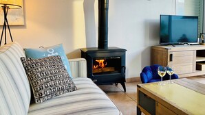 Un salon comprenant un canapé, un téléviseur, un meuble en bois et une cheminée.