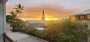 Une église dotée d’un clocher, entourée de verdure, et un bâtiment avec un toit en pente.