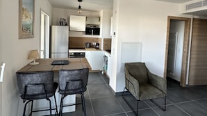 A modern kitchen with a dining area, a chair, and a small table. - new luxury residence (1 bedroom) Sea view, Citadel and port of Calvi (Calvi)
