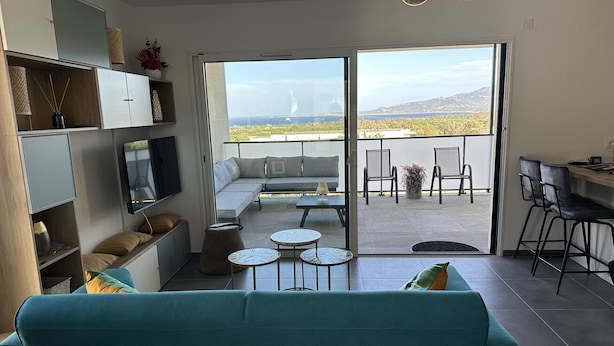 A modern living room with a teal sofa, a TV, and a balcony with a view of the sea. - new luxury residence (1 bedroom) Sea view, Citadel and port of Calvi (Calvi)