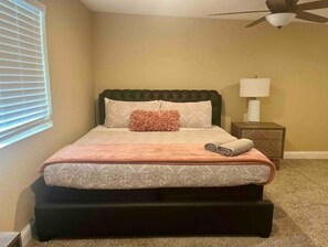 Un dormitorio con cama, mesita de noche, lámpara y ventilador de techo.