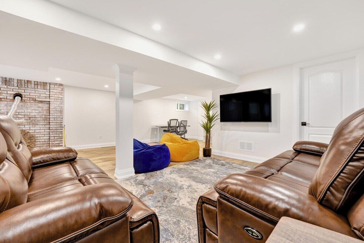 Una sala de estar moderna con sillones de cuero, un televisor de pantalla plana y una pared de acento de ladrillo.