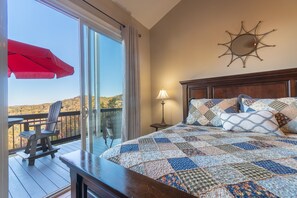 Une chambre à coucher avec un grand lit, une vue sur l’extérieur, un parapluie rouge et une tête de lit en bois.