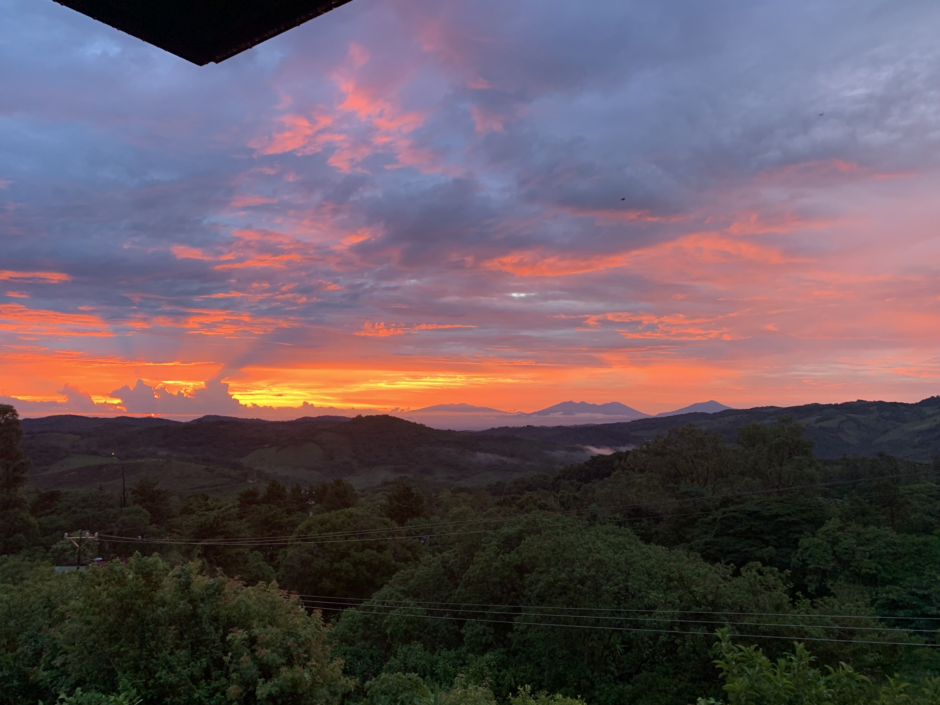 Ein Sonnenuntergang über einer gebirgigen Landschaft mit dichtem Wald.
