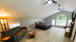 A spacious loft bedroom with a large bed, a sofa, and a ceiling fan. - Mountain Ridge Retreat - Private & Peaceful Getaway. Family & Pet Friendly (West Park)