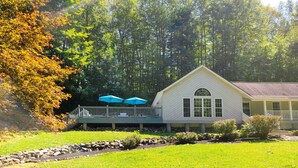 A white building with a covered deck and two blue umbrellas. - Mountain Ridge Retreat - Private & Peaceful Getaway. Family & Pet Friendly (West Park)