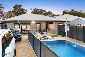 Una casa moderna con piscina, mobiliario exterior y zona de barbacoa.