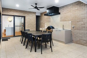 Una cocina moderna con un salpicadero de pared de ladrillo, una parrilla empotrada y un comedor con mesa y sillas.