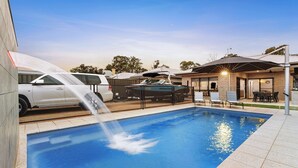 A swimming pool with a water feature, a covered boat, and outdoor seating.