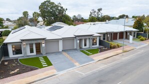 Un edificio residencial moderno con paneles solares, un garaje y un césped bien cuidado.