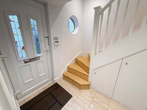 A staircase leading to a landing with a white door featuring stained glass windows.
