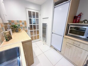 Eine moderne Küche mit Einbauofen, Spüle und einer Tür zum Balkon.