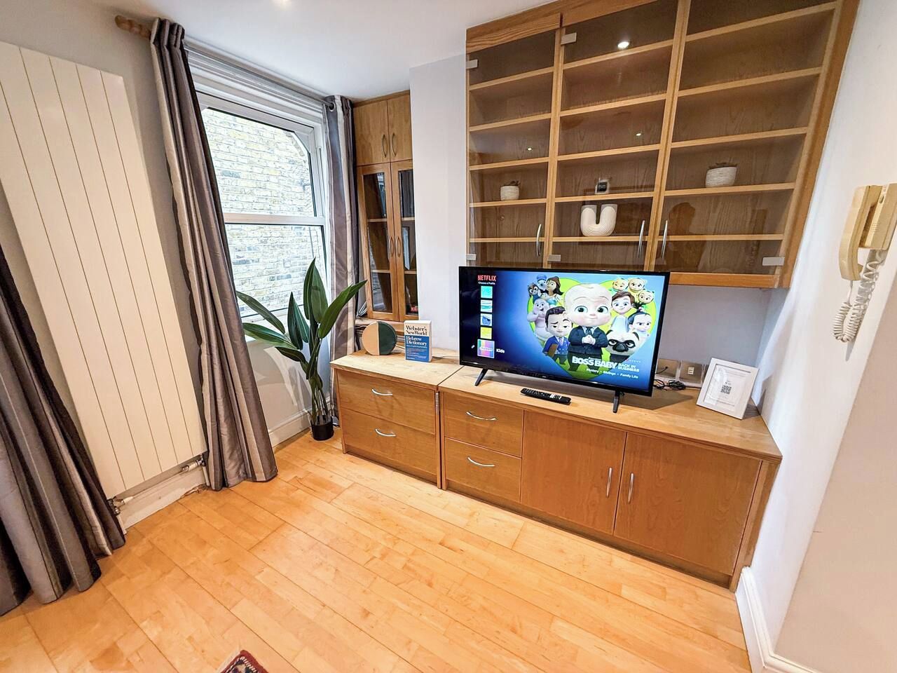 Een woonkamer met een houten kast, een televisie en een potplant.