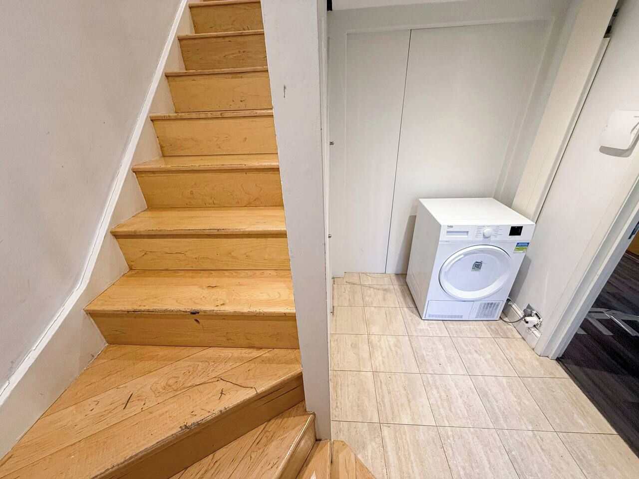 A wooden staircase leading to a laundry area with a washing machine.