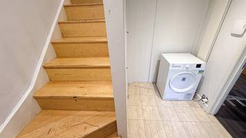 A wooden staircase leading to a laundry area with a washing machine.