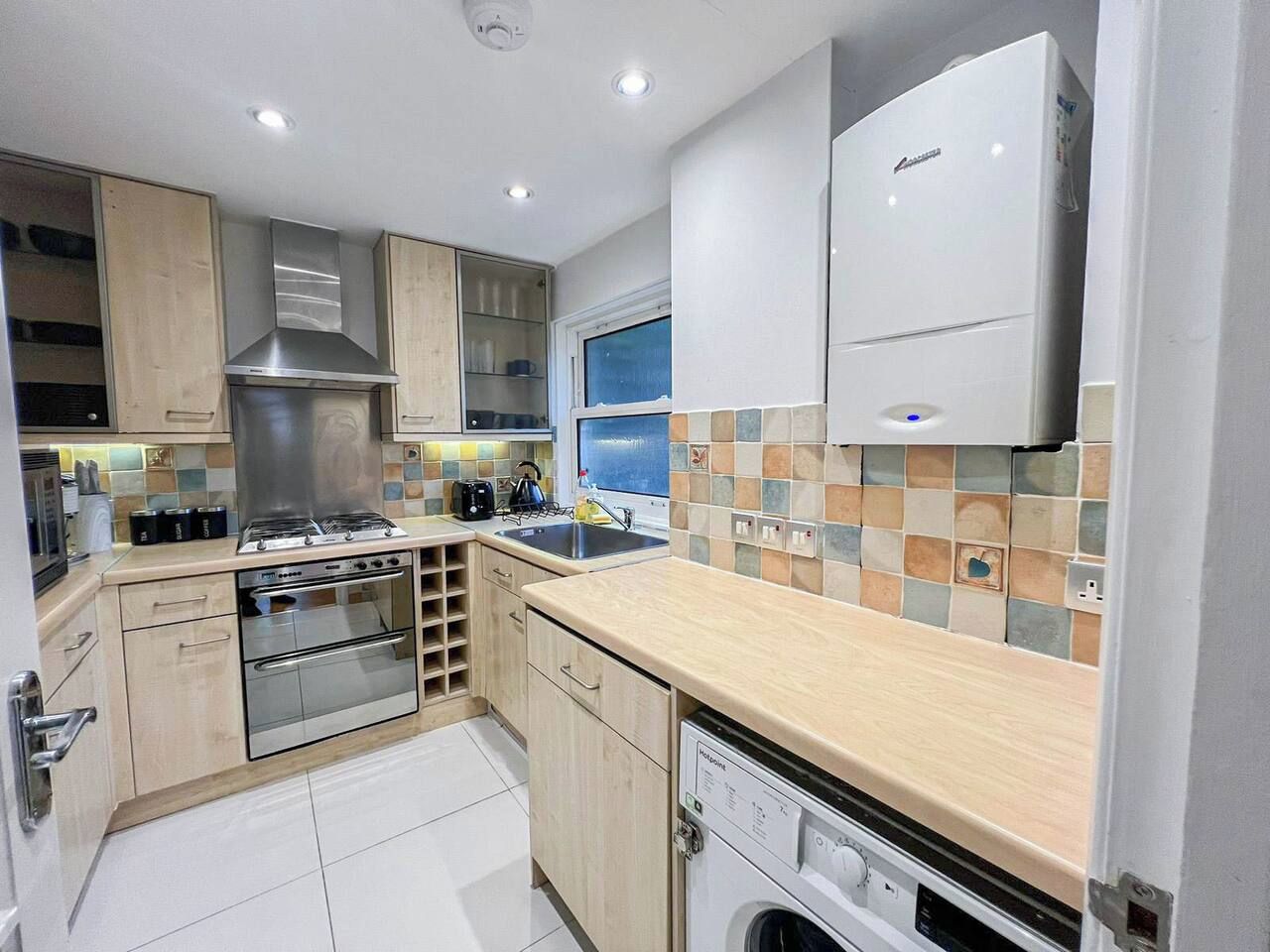 A modern kitchen with stainless steel appliances, wooden cabinets, and a tiled backsplash.