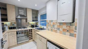 A modern kitchen with stainless steel appliances, wooden cabinets, and a tiled backsplash.