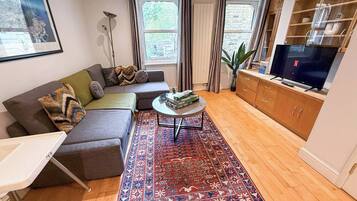 A living room with a sofa, a coffee table, a rug, and a TV.