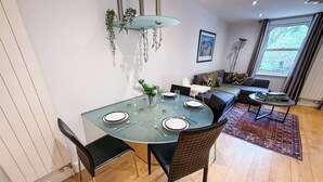 Un comedor con una mesa de vidrio, sillas negras y un tapete rojo.